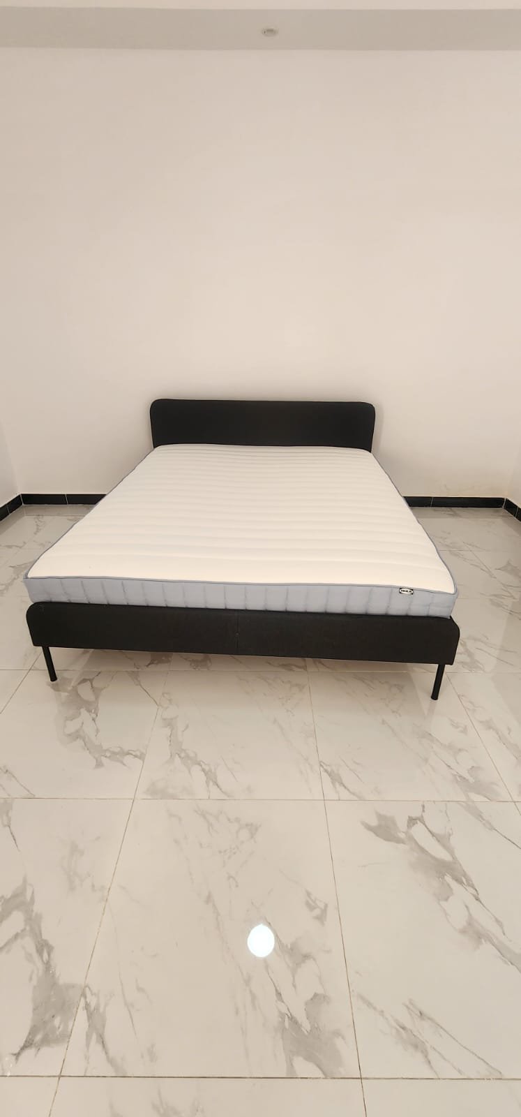 Modern dark grey fabric upholstered queen bed frame with clean IKEA