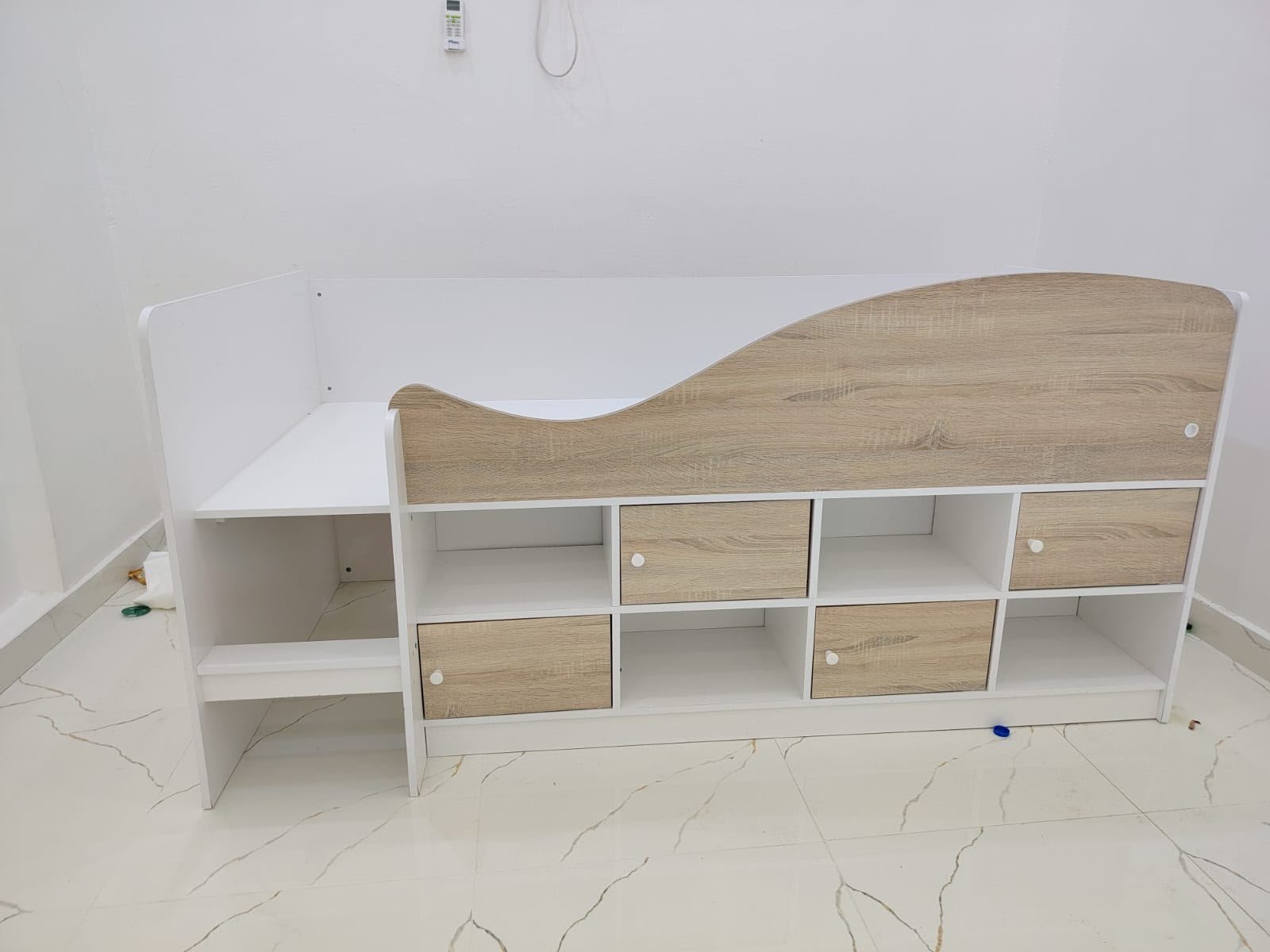 Modern white and light oak single cabin bed frame with built-in under-bed storage drawers, open display shelves, and side compartment at Fairy of Fortune Used Furniture Abu Dhabi