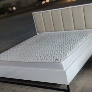 Modern white wooden double bed frame featuring a beige vertical channel-tufted upholstered headboard and plush comfortable mattress at Fairy of Fortune Used Furniture Abu Dhabi